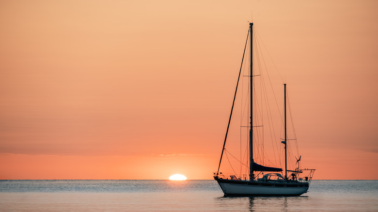 Silhouette Of A Pleasure Boat Moored In The Harbor Of The Coastal And Touristic Village Of Collioure (Cotlliure). France During A Beautiful Sunrise On The Waters Of The Mediterranean Sea. Orange Sky.