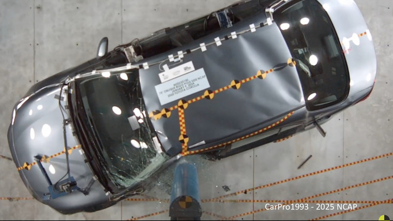 An overhead screenshot from the NHTSA side pole impact crash test of a gray 2025 Toyota Corolla after it hit the pole