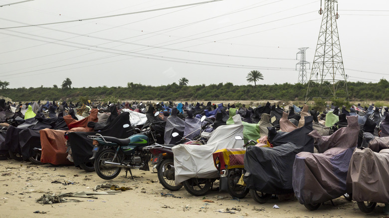 motorcycles parked in a parking lot, covered with tarps