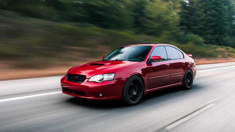 Seattle, WA, USA1/22/2022Red Subaru Legacy driving on the highway with trees in the background