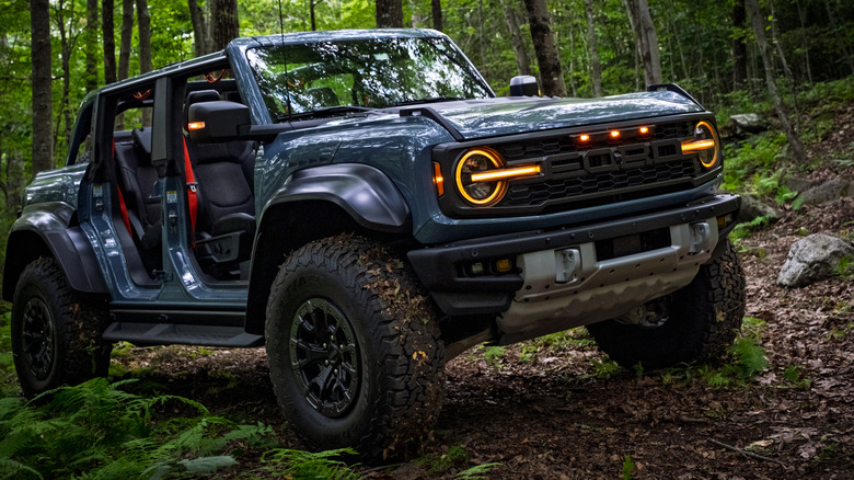Colchester, Connecticut, USA - 08-28-2025 A 2025 Ford Bronco Raptor withAzure Gray Metallic Tri-Coat paint parked off-road in a forest with doors removed, showcasing rugged design, off-road capability, and adventure lifestyle appeal.