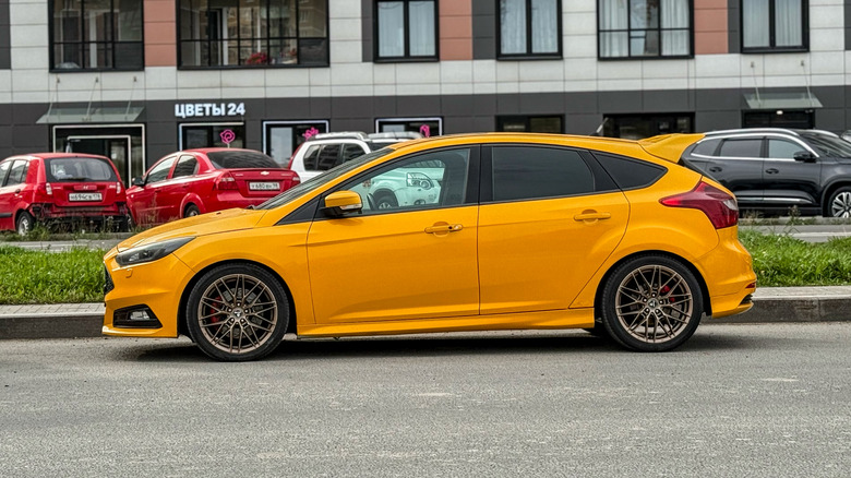 St-Petersburg, Russia, July 3, 2025: Yellow Ford Focus ST 4-generation for the European market. Stands on Parking slot. Orange Ford Focus ST Turnier sport estate car parked on street at the day. USA.