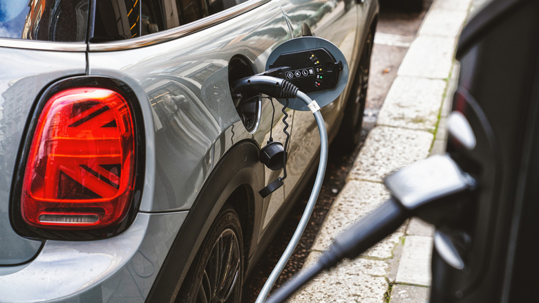 A Mini Cooper SE parked on the street with an electric charging cable plugged in