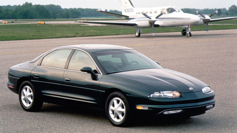 Front 3/4 view of a black Oldsmobile Aurora at an airport