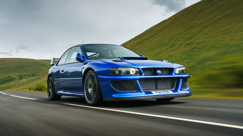 A blue Prodrive P25 on a country road, a restomod tribute to the Subaru Impreza WRX STI 22B