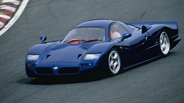 Front 3/4 view of a blue Nissan R390 driving on track