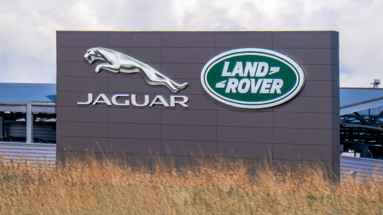 The iconic Jaguar and Land Rover logos are prominently displayed connected a modern building, signifying luxury automotive excellence and British heritage.