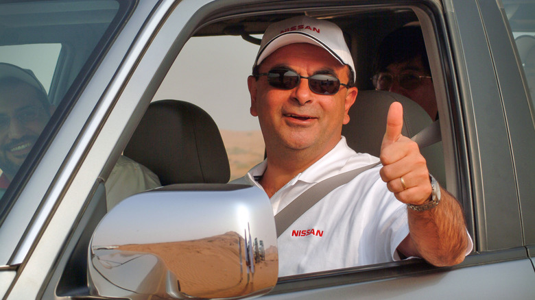 Carlos Ghosn giving a thumbs up from a car