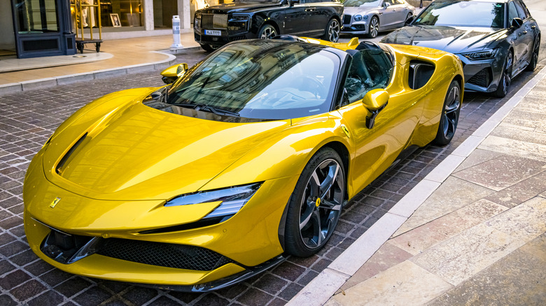 Street-parked Ferrari in front of a Rolls-Royce and Bentley