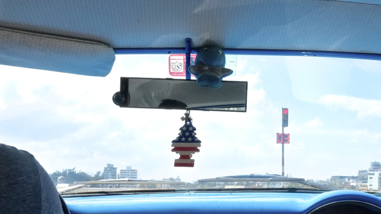 tree air freshener hangs from a car's rearview mirror