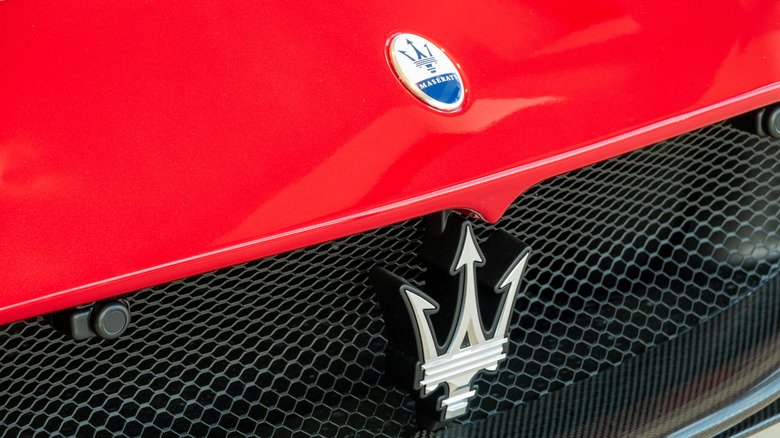 Close-up view of red Maserati vehicle front radiator grille, metal bars, logo Maserati tridents. Copenhagen, Denmark - May 15, 2025.