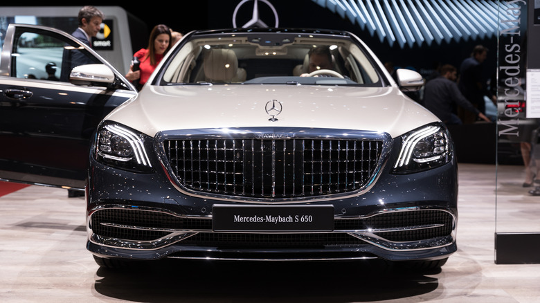 Two-tone Mercedes-Maybach S 650 seen from in front parked at an indoor car show with passenger side door open