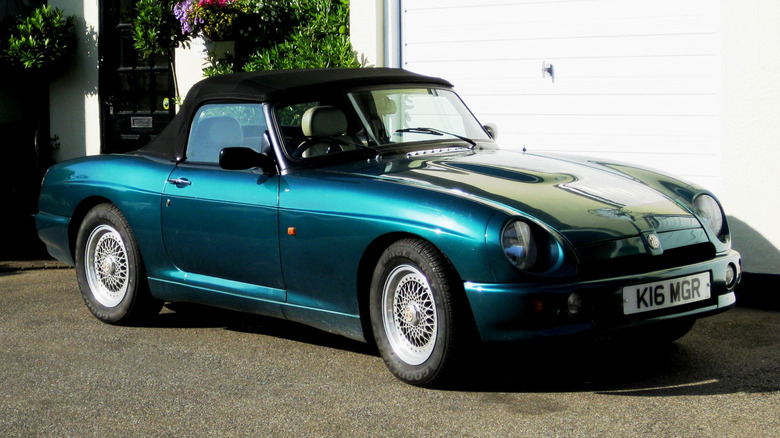 Green MG RV8 roadster seen from right front parked in front of a building