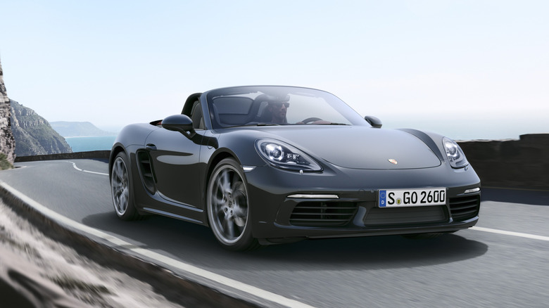 A 2025 Porsche 718 Boxster with its top down on a winding road