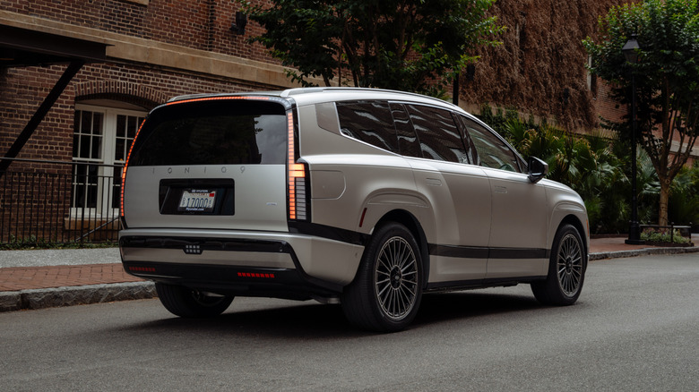 A rear 3/4 view of a 2026 Hyundai EV9 parked on a city neighborhood street