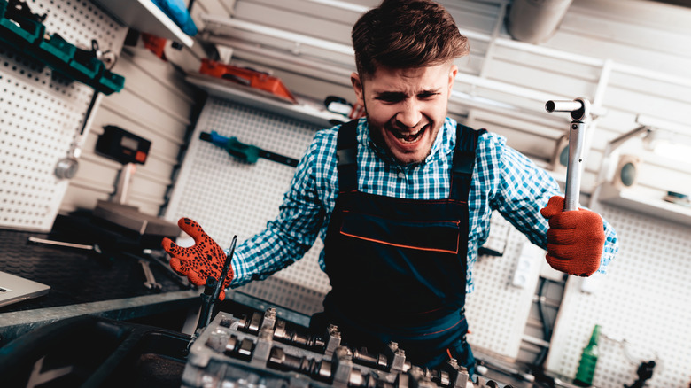 Frustrated DIY mechanic working on a vehicle.