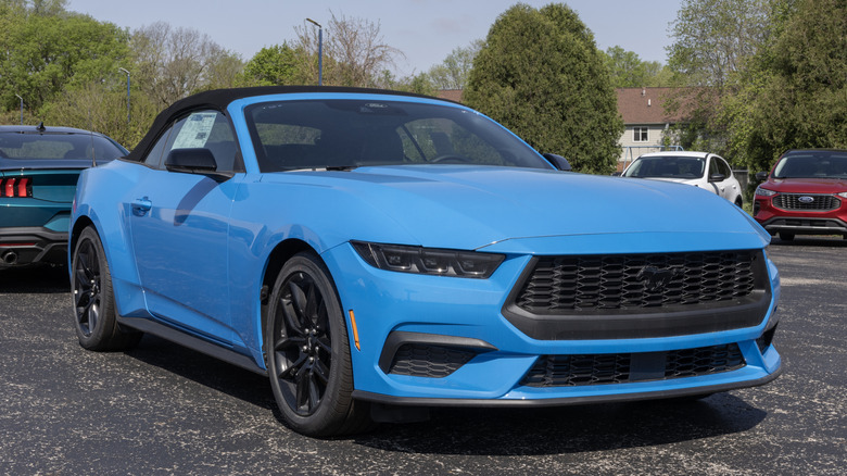 a grabber blue ford mustang sitting on a dealership lot