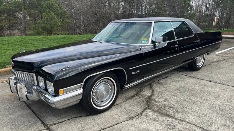 Front three quarters shot of a giant black '71 Cadillac Sedan DeVille parked in front of grass