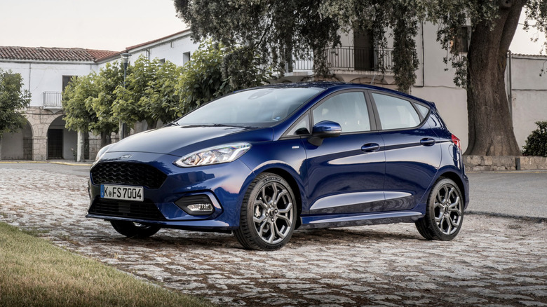 a blue Ford Fiesta parked in front of an old estate