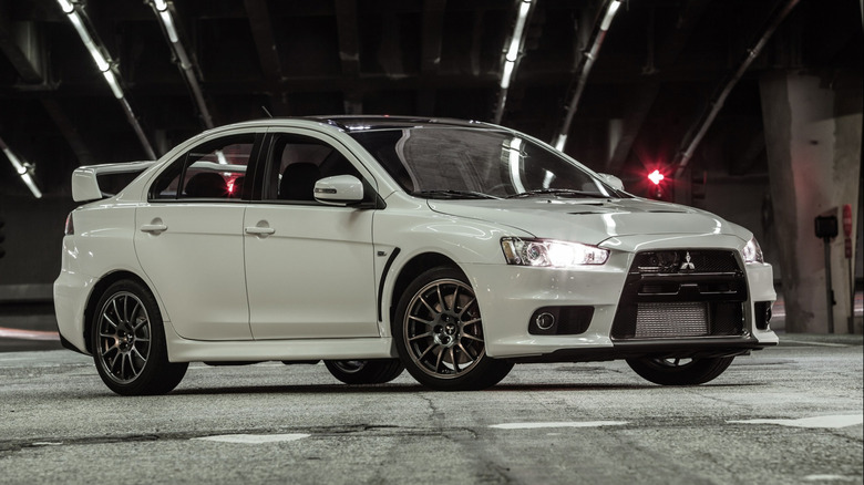 An off-white Mitsubishi Lancer Evolution Final Edition parked under a bridge