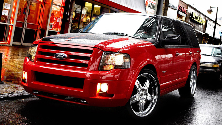 A black and red Ford Expedition parked on a wet city street