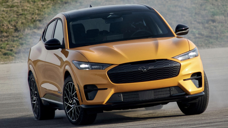 A yellow Ford Mustang Mach-E drifting sideways in a parking lot