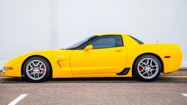 Side view of a yellow C5 Z06 parked in front of a white wall