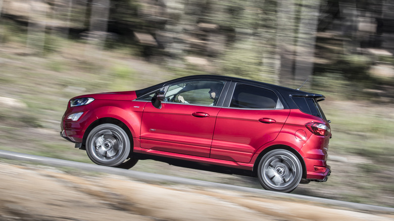 Side position of a reddish EcoSport driving connected a upland road