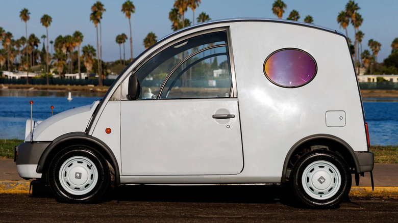 Side view of a white Nissan S Cargo parked in front of a body of