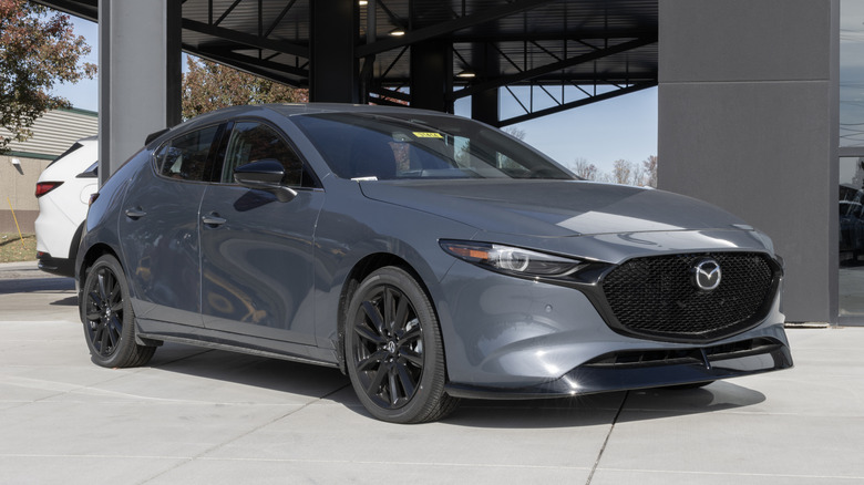 A Mazda Mazda3 sits parked under a structure.