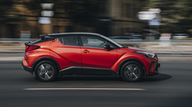 A red Toyota C-HR moves down a highway.