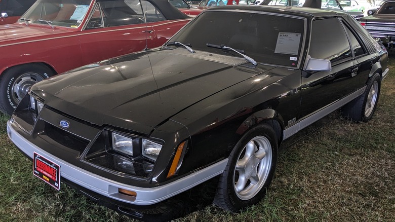 A black 1985 Ford Mustang GT parked at a car auction