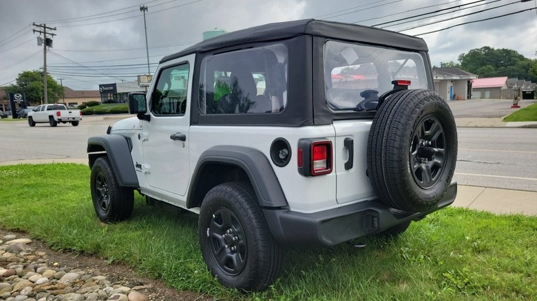 rear three-quarters shot of a BASE white 2 door wrangler parked on grass in front of a street