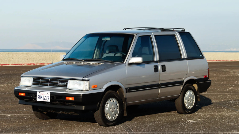 front three-quarters shot of a Silver 1986 Nissan Stanza XE parked on asphalt in front of sand and a blue sky