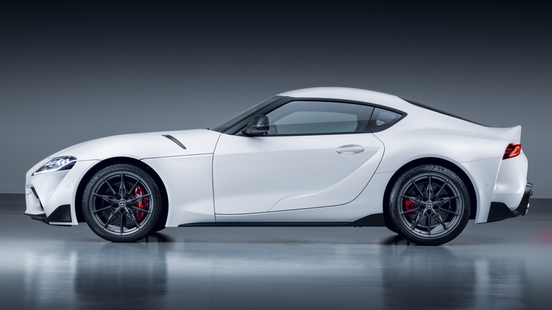 A white Toyota Supra parked indoors with a gray background.