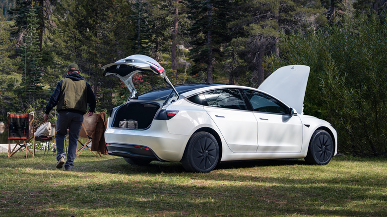 Rear 3/4 view of a white Tesla Model 3 with the trunk and frunk open