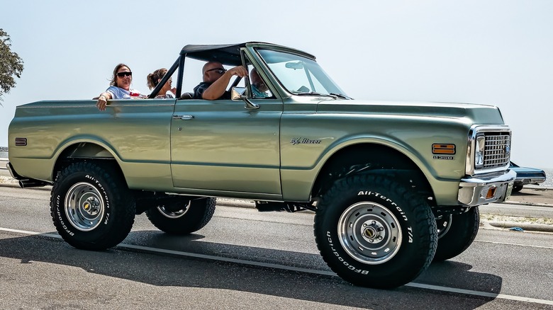 A light green 1972 Chevrolet K5 Blazer with three passengers as well as the driver