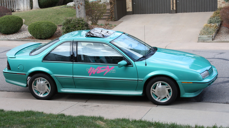 side view of a teal Chevrolet Beretta with a pink Indy 500 badge on the side