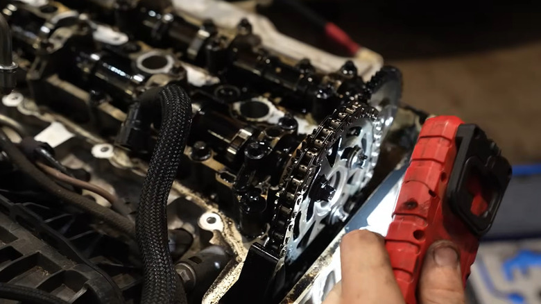 A person using an orange flashlight to inspect a BMW N47 timing chain