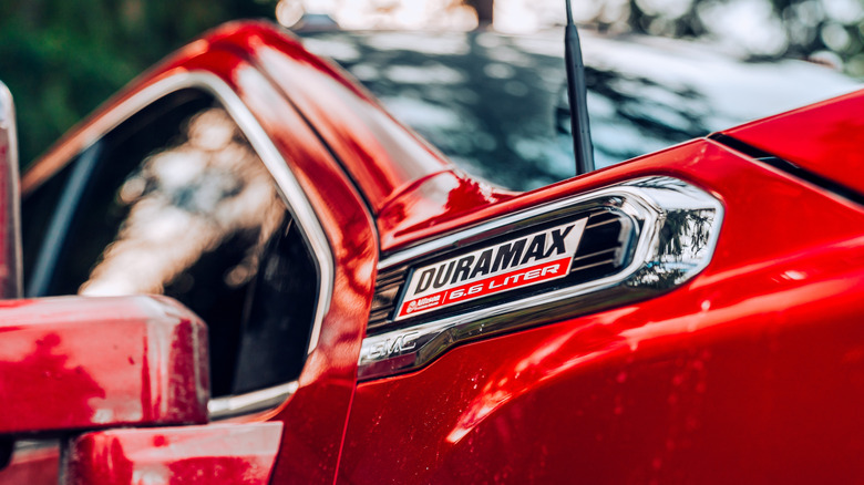 A Duramax 6.6L diesel fender badge on a red GMC truck