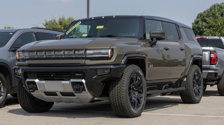 A dark brown GMC Hummer EV parked on a GMC dealership lot.