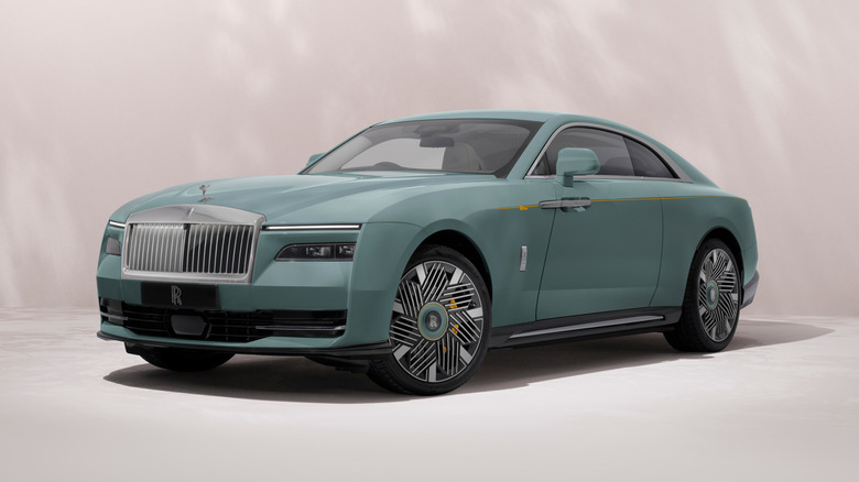 Front three-quarters shot of a light blue Rolls Royce Spectre in a studio in front of a blurry pale pink backdrop