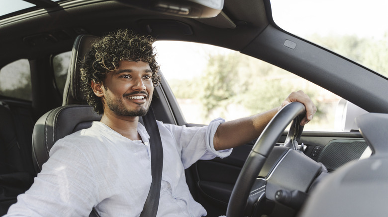 A young male driver at the wheel of a car