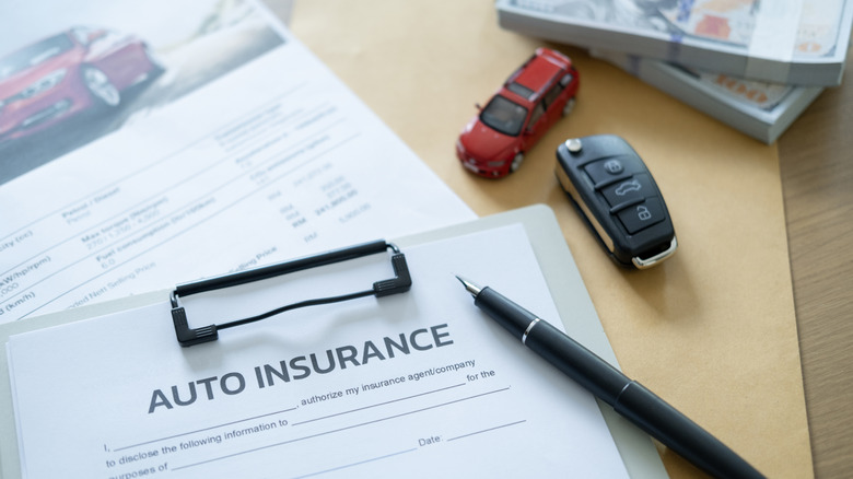 A clipboard with a car insurance form attached, placed on a desk