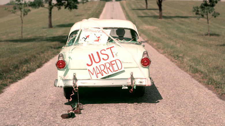 A classic car driving away with a "just married" sign