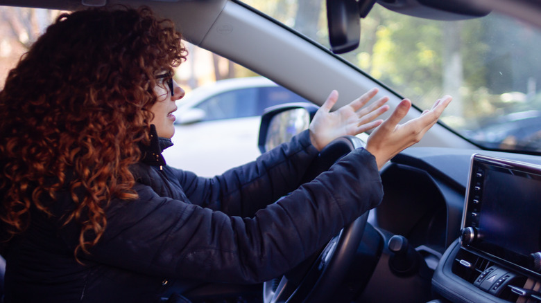A frustrated driver with their hands over the steering wheel