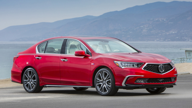 Front three quarters shot of a red RLX parked in a parking lot in front of a view of the ocean and mountains