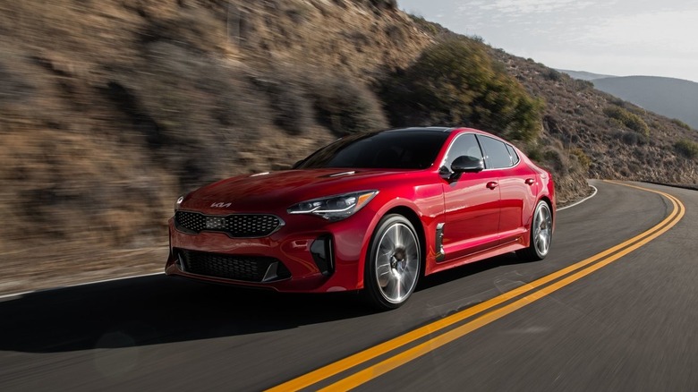 Front three quarters shot of a red Kia Stinger driving around a corner on a mountain road