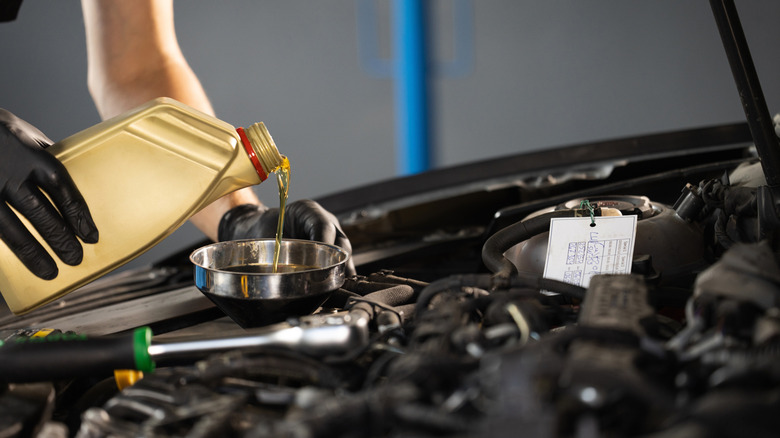 Mechanic pouring oil into a vehicle's engine.