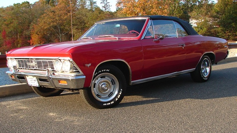 Red 1966 Chevrolet Chevelle Malibu SS 396 convertible seen from left front parked next to a lake